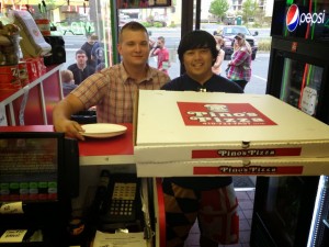 two guys holding two jumbo sized Pino's Pizza boxes in Pino's Pizza of OCMD
