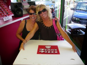 two women holding XX Large pizza from Pino's Pizza