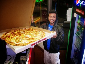 man holding jumbo sized half pepperoni Pino's Pizza in OCMD