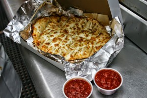 cheesy breadsticks on foil with two cups of sauce from Pino's Pizza